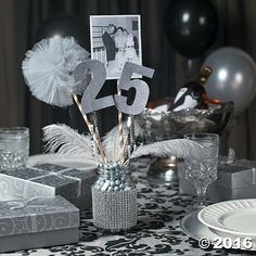 the table is set with silver decorations and gifts for someone's 25th birthday party