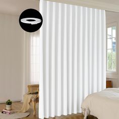 a bedroom with white curtains and a black circle on the window sill above the bed