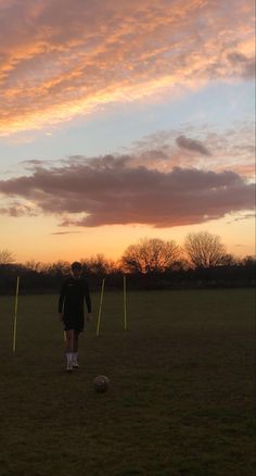 a man standing on top of a lush green field next to a soccer ball under a cloudy sky