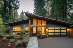 a large house with lots of windows in the front and side of it, surrounded by trees