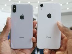 two people holding up their new iphones in front of the camera, one is white and the other is silver