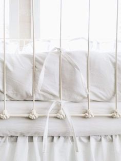 a crib with white bedding and pillows