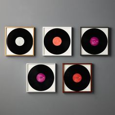 four black and pink records are hanging on the wall in front of a gray background