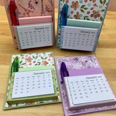 four calendars are sitting on a table with pens and notebooks in front of them