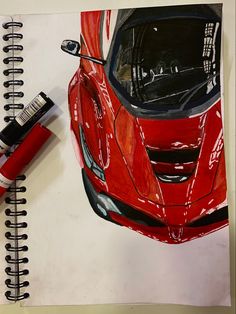 a drawing of a red sports car on a notepad next to a marker pen