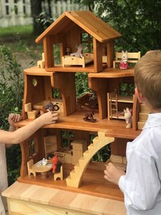 two children playing with a wooden doll house