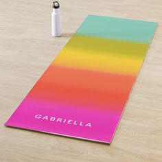 a yoga mat with the name gabrilla on it next to a water bottle