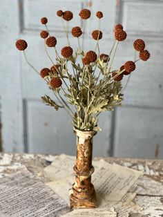 a vase filled with lots of dried flowers on top of a table next to a door