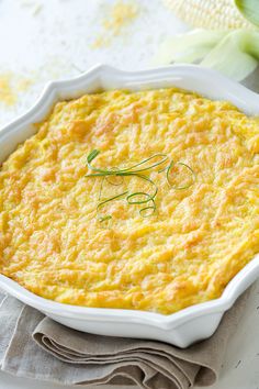 a casserole dish with cheese and herbs in it on a white tablecloth