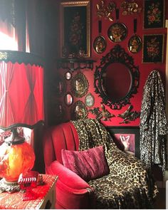 a living room with red walls, leopard print couches and mirrors on the wall