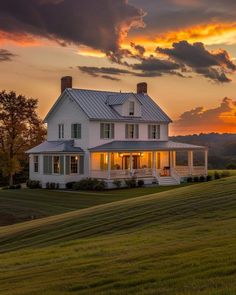 a large white house sitting on top of a lush green field under a cloudy sky