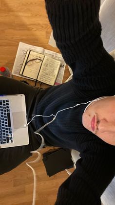 a person laying on the floor with headphones in front of their face and laptop