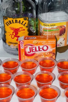 there are many cups and bottles on the table with orange juice in them, including jello