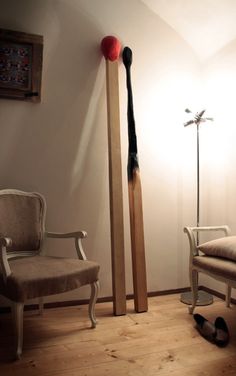 a room with two chairs, a chair and a large wooden stick in it's corner