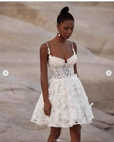 a woman in a white dress standing on rocks