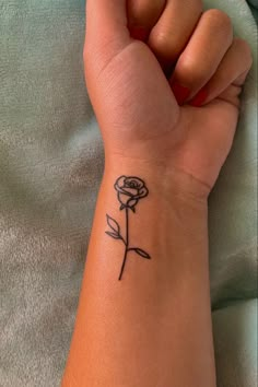 a woman's wrist tattoo with a single rose on the left side of her arm