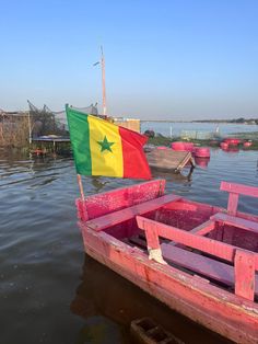 a boat with a flag on it floating in the water next to other small boats