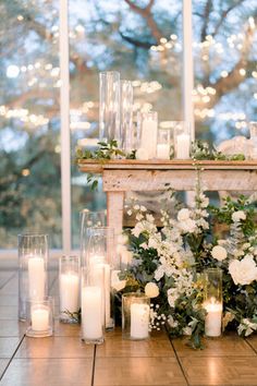 candles and flowers are arranged on the floor in front of an open window with lights