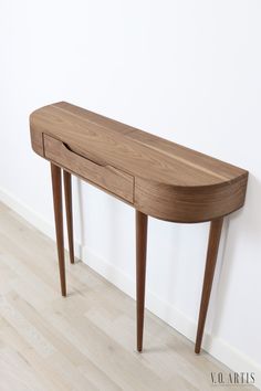 a wooden table sitting on top of a hard wood floor next to a white wall