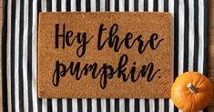 a door mat with the words hey there pumpkin on it next to an orange pumpkin