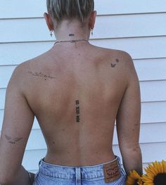 the back of a woman's body with tattoos and sunflowers in front of her