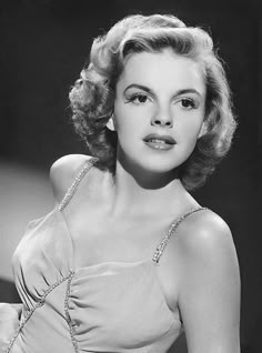 a black and white photo of a woman wearing a halter top with chains on it