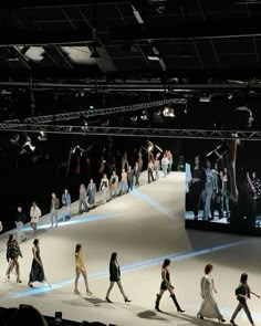 many people are walking down the runway at a fashion show in front of a large screen