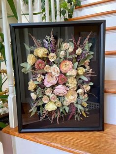 an arrangement of flowers is displayed in a frame on the stairs at the bottom of a flight of steps