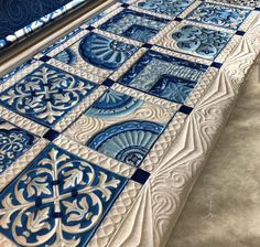 a blue and white quilt is laying on top of the floor in front of a window