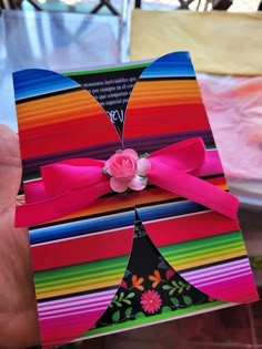 a person holding up a colorful card with a pink rose on the top of it