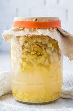 a jar filled with food sitting on top of a white cloth covered table next to a wooden spoon