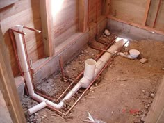 an unfinished bathroom with pipes and toilet paper on the ground in front of wooden walls