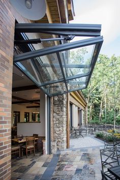 an outdoor patio with tables and chairs next to a brick wall that has glass on it