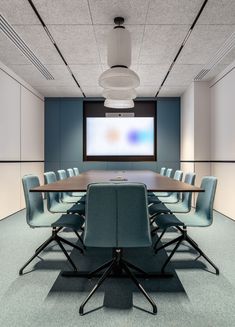 an empty conference room with blue chairs and a projector screen