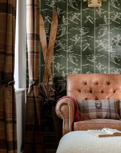 a chair and ottoman in front of a green wallpapered room with two lamps