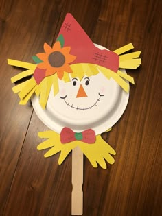 a paper plate with a scarecrow on it and a wooden stick sticking out of it