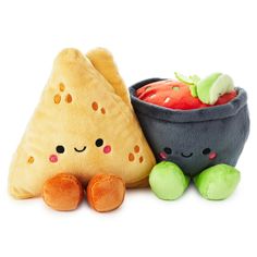 two stuffed toys are sitting next to each other on a white surface, one has a bowl and the other has a slice of fruit in it's mouth