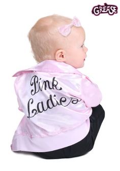 a baby sitting on the ground wearing a pink jacket and black pants with words written on it