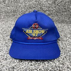 a blue hat with an air show logo is laying on the floor in front of a carpet