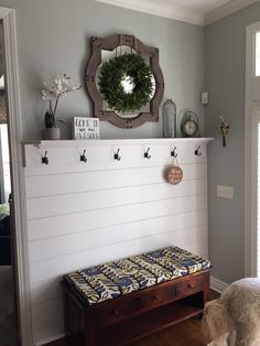 a dog is sitting in front of a bench with a wreath on the wall above it