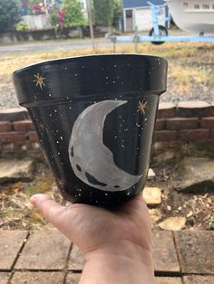 a hand holding up a cup with the moon painted on it