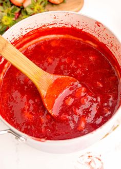 a wooden spoon in a pot of red sauce