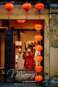 an open window with orange lanterns hanging from it's sides and two mannequins in the doorway