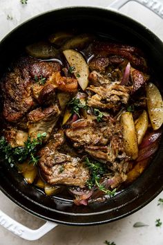 a pot filled with meat and potatoes on top of a table