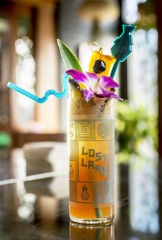 a glass filled with liquid and flowers on top of a table