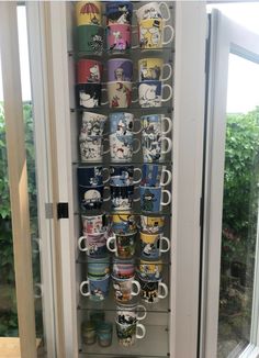 there are many coffee mugs on the shelf in this cabinet and it is full of them