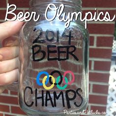 a person holding up a glass jar with the words beer olympics written on it