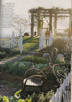 an old chair sitting in the middle of a garden next to a white picket fence