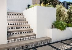 the stairs are decorated with black and white tiles, while plants grow on each step