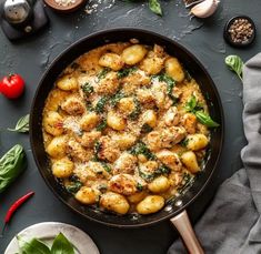 a skillet filled with pasta and spinach on top of a black countertop